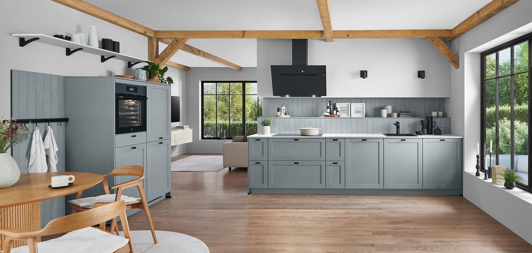 Cuisine gris-bleu à façades à cadre installée sous une charpente apparente, dans une maison ancienne ouverte sur le séjour