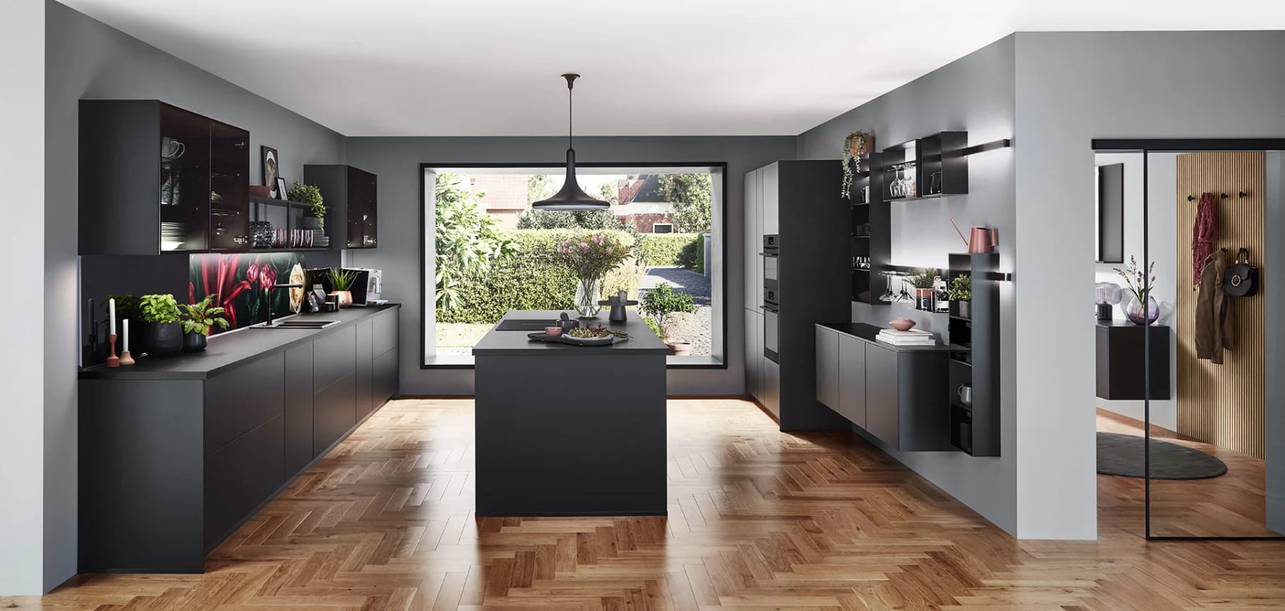 Cuisine ouverte aux façades anthracite mates, îlot central et parquet à bâtons rompus, ouverte sur le jardin