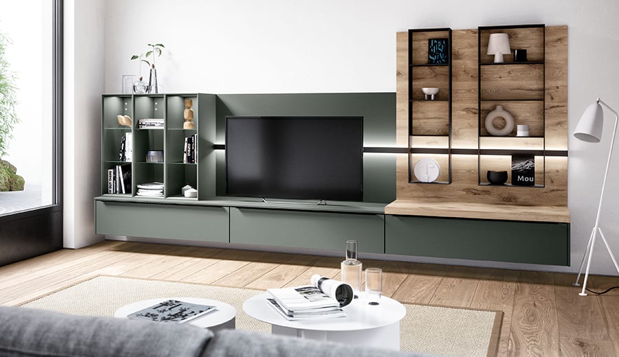 Mur de séjour vert minéral : meuble télé suspendu, vitrines éclairées et étagères en décor chêne encadrées de métal noir, table basse ronde au premier plan