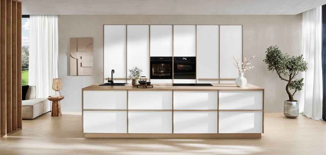 Cuisine blanche mate à îlot, façades cernées d’un cadre de bois clair et plan de travail fin en décor chêne