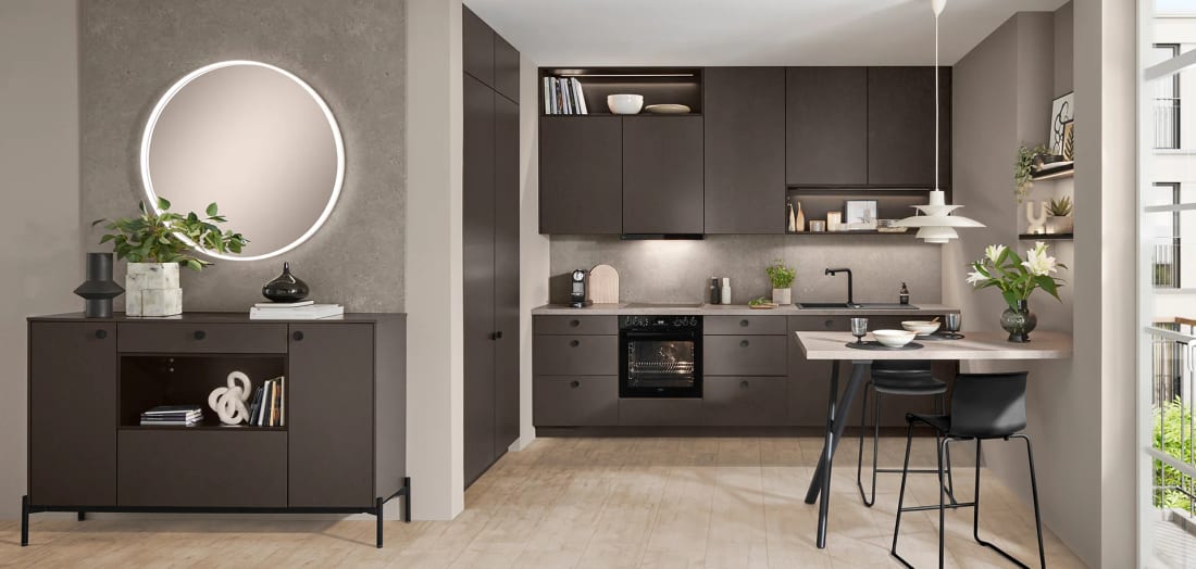 Cuisine linéaire à façades café structurées, bandeau haut fermé et table ronde dans le prolongement